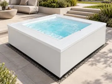 Infinitas The One Outdoor-Whirlpool in Weiß auf einer Terrasse mit Stufen und Seeblick